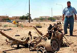 En mann betrakter en bilvrak etter angrepet i Tikrit søndag. Foto: Bassem Daham, AP