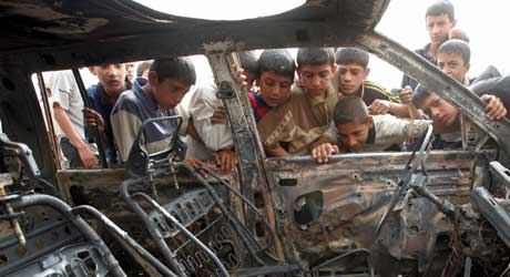 Storøyde irakiske barn tar en utbrent bil i øyesyn. 11 ble drept og 29 skadd da bomben eksploderte (Scanpix/Reuters) 