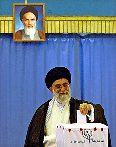 Under bildet av "landsfaderen" ayatollah Khomeini avgav dagens øverste leder ayatolla Ali Khamenei stemmen sin i det iranske presidentvalget. Foto: AP/Scanpix