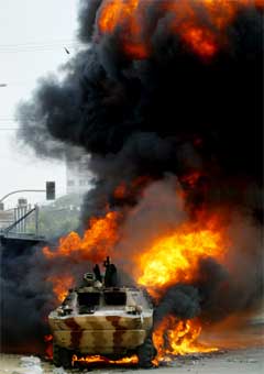 En palestinsk stridsvogn brenner etter å ha blitt satt fyr på i sammenstøtet i Gaza i dag. (Foto: Scanpix/AP/H. Moussa)