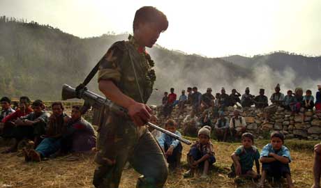 Maoistisk soldat går inn i landsby med barn. Nepal er et av de mange land der barn blir soldater, påpeker Amnesty og FN (Scanpix/AP) Maoistisk soldat går inn i landsby med barn. Nepal er et av de mange land der barn blir soldater, påpeker Amnesty og FN (Scanpix/AP)
