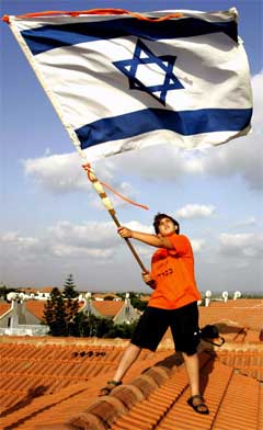 Ein ung aktivist viftar med det israelske flagget på eit hustak i Neve Dekalim. (Foto: AFP/Scanpix) Ein ung aktivist viftar med det israelske flagget på eit hustak i Neve Dekalim. (Foto: AFP/Scanpix)