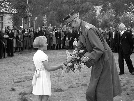 Kong Haakon besøker Melbu for å se på gjenreisningen av byen etter 2. verdenskrig. Her får kongen blomster av en liten jente. Foto: NTB arkiv / Scanpix