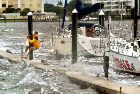 Ein mann klamrar seg fast til ein stolpe på båthamna i Palm Beach. (Foto: AP/Scanpix)