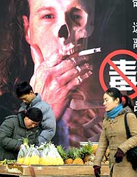 En fruktselger foran en anti-røykeplakat i Beijing i mars i år. (Foto: AFP/Scanpix)