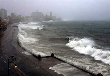 Bølger slår over strandpromenaden El Malceon i Havana. Innbyggerne holder seg imidlertid innendørs til 