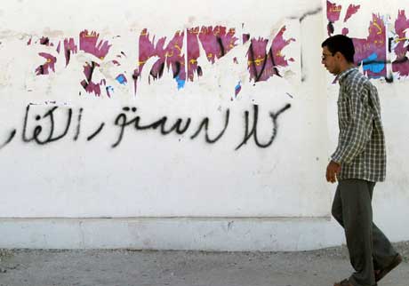 En mann passerer en nedrevet valgplakat i Falluja (Scanpix/Reuters)