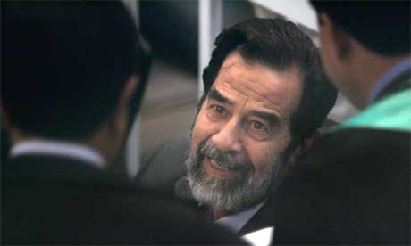 Saddam Hussein i diskusjon med sine advokater i gr. (Foto: Scanpix / AP)