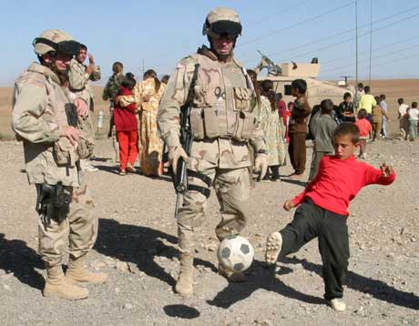 Amerikanske soldater spiller fotball med en gutt i Mosul. (Foto: Scanpix / AP)