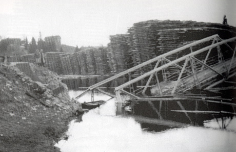 Nybrua over Andelva, sprengt i 1940. I bakgrunnen tømmerlunner som venter på å bli cellulose og papir. Foto: Leif H. Eriksen. Nybrua over Andelva, sprengt i 1940. I bakgrunnen tømmerlunner som venter på å bli cellulose og papir. Foto: Leif H. Eriksen.