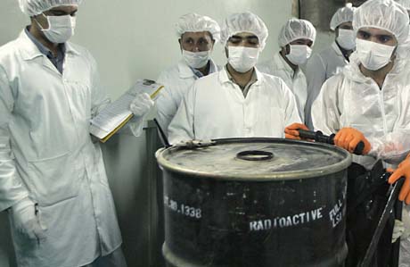 Seglet brytes: Tekniskere flytter en tønne med radioaktivt uran, forseglet av IAEA. (Foto: B.Mehri, AFP)