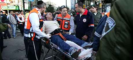 Redningsarbeidere tar seg av en av de sårede i Tel Aviv. Foto: Ariel Schalit, AP