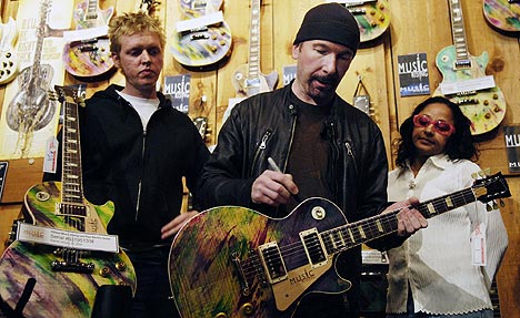 John Henry Kelly, som fikk sitt studio ødelagt i orkanen Katrina, ser på at The Edge fra U2 signerer en gitar på The Guitar Centre i Los Angeles. Foto: Chris Pizzello, AP Photo / Scanpix.