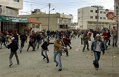 Palestinske ungdommer kaster stein mot hovedkvarteret til observatørstyrken i Hebron.(Foto:AP/Scanpix)