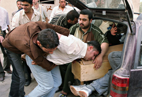 En slektning klamrer seg til kisten til en av de som ble drept av bomber i Bagdad i dag. (Foto: AP/Scanpix)