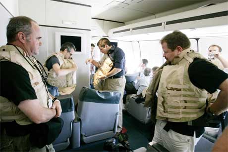 Journalister om bord på presidentflyet Air Force One tar på seg skuddsikre vester før flyet lander i Bagdad. (Foto: Larry Downing/Reuters/Scanpix)