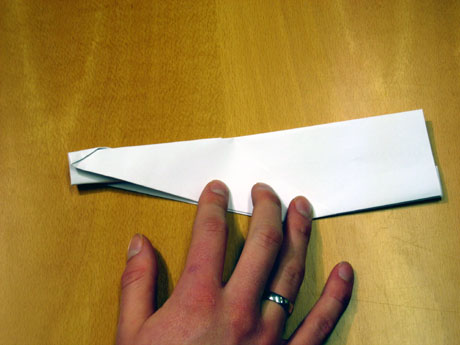 11. Her har eg bretta ned vengane på begge sider. Legg merke til den vesle papirkanten som er komen i midten, det er han du skal halde i når du sender flyet.