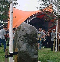 Minnesteinen som er blitt satt opp. I bakgrunnen kan man se det orange teltet, der tragedien utspant seg under fjorårets festival.